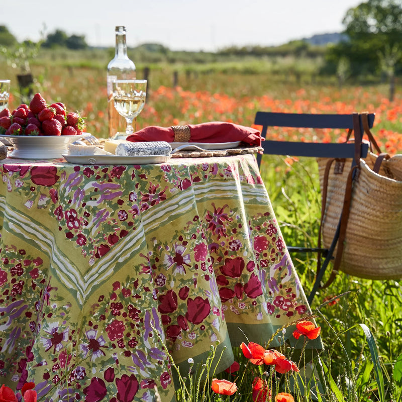 Caravan Home | 59 x 86 Red & Green Tablecloth displayed on a table set outdoors, highlighting its handprinted craftsmanship inspired by French gardens.