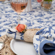 Granada Cornflower Blue Napkins set of 6, featuring a floral pattern with pomegranates, displayed with wine glass on a dining table setting.