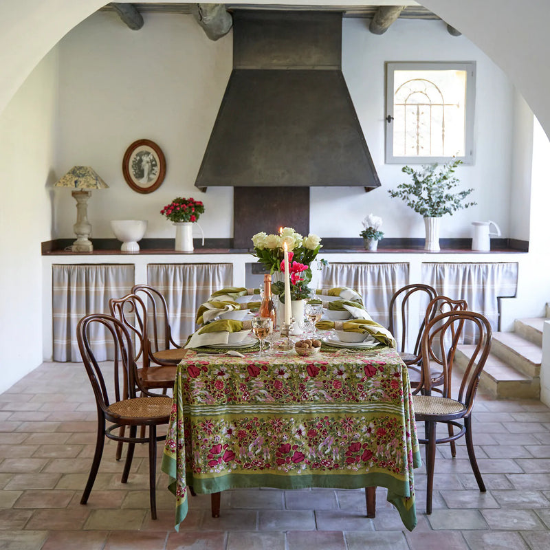 Caravan Home 59 x 86 Red & Green Tablecloth, handprinted with floral patterns, adorning a dining table set, reflecting Southern France's lush garden inspiration.