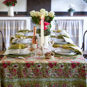 Caravan Home 59 x 86 Red & Green Tablecloth featuring a floral design, displayed on a table with candles and flowers, showcasing artisanal craftsmanship.