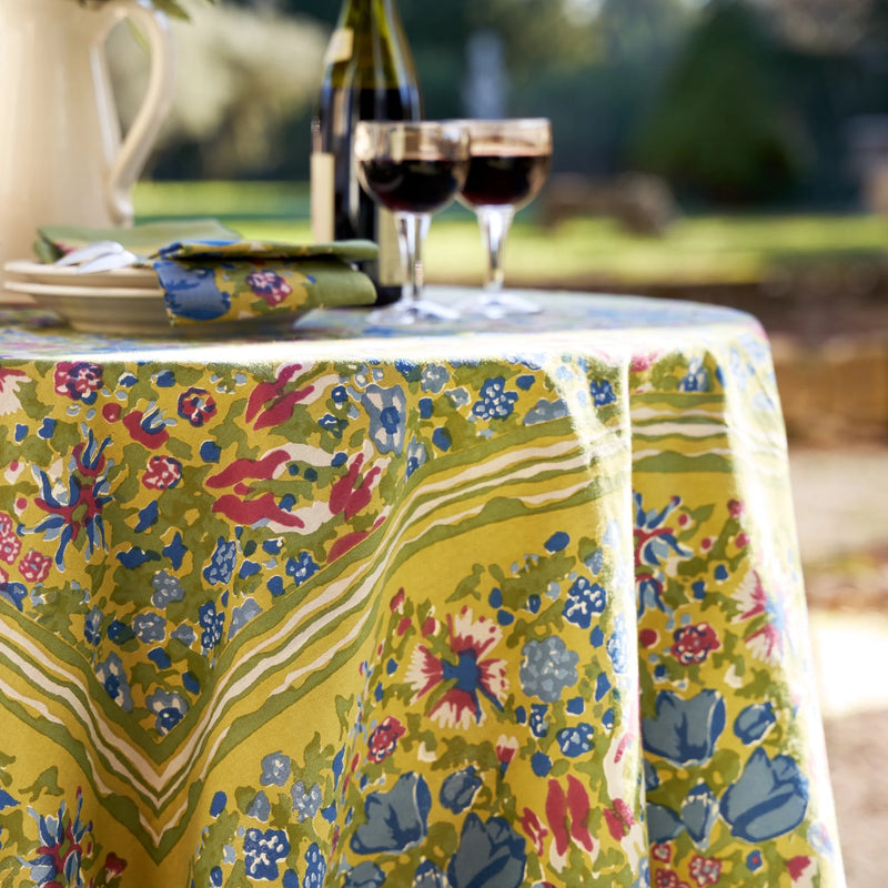 Caravan Home | 71 x 71 Jardin Blue & Vert Tablecloth on a set dining table adorned with wine glasses, showcasing handprinted floral motifs inspired by Southern France gardens.
