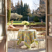 Caravan Home 71 x 71 Jardin Blue & Vert Tablecloth draped over an outdoor table, adorned with white roses in a pitcher.