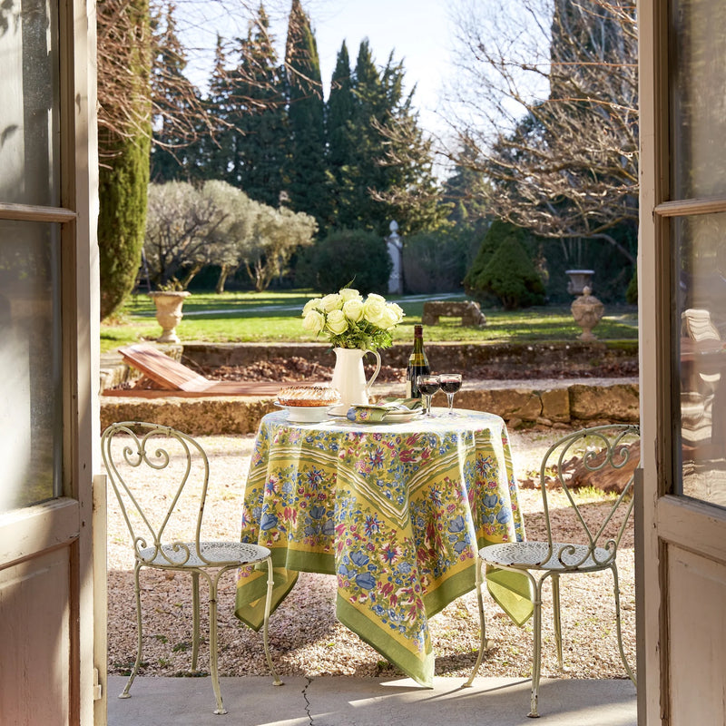Caravan Home | 71 x 106 Jardin Blue & Vert Tablecloth elegantly drapes an outdoor table, adorned with white roses in a pitcher, embodying Southern France's garden charm.
