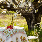 Caravan Home 71 x 106 Fraises des Bois Blue Tablecloth elegantly displayed outdoors with wine, strawberries, and a white chair under a tree.