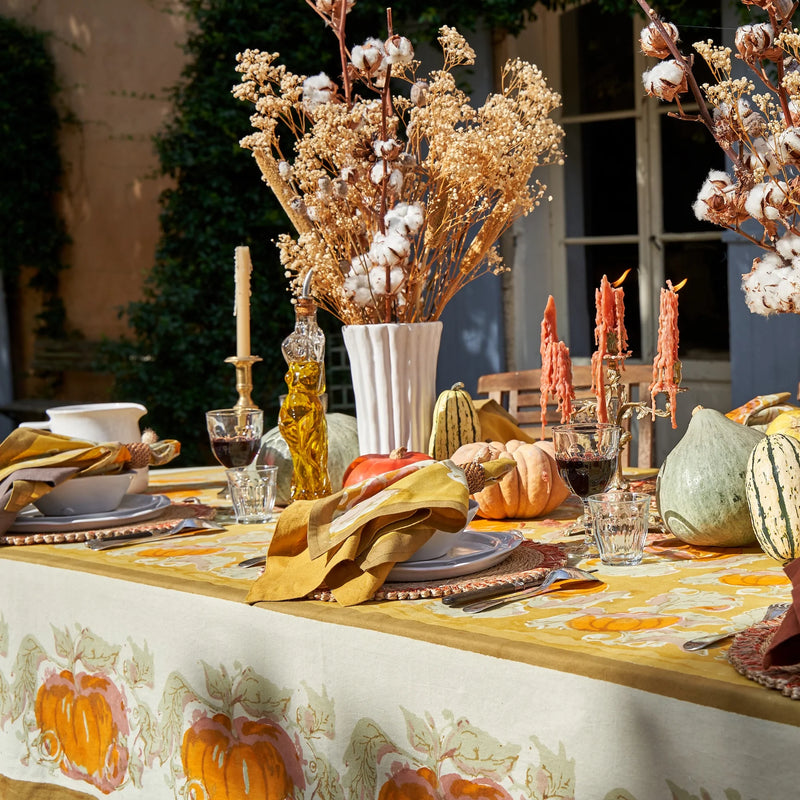 Caravan Home's Dijon Everyday Napkins Set on a table, accompanied by decorative elements like a vase with dried flowers and a pumpkin.