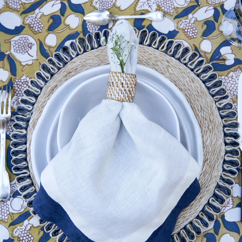 Caravan Home 21 x 21 White Everyday Napkins, set of 4, elegantly folded on a plate, showcasing refined craftsmanship and luxurious linen texture.
