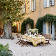 Caravan Home's 59 x 86 Forest Harvest Grey & Mustard Tablecloth elegantly drapes an outdoor table, showcasing artisanal craftsmanship with intricate fruit and vine patterns.