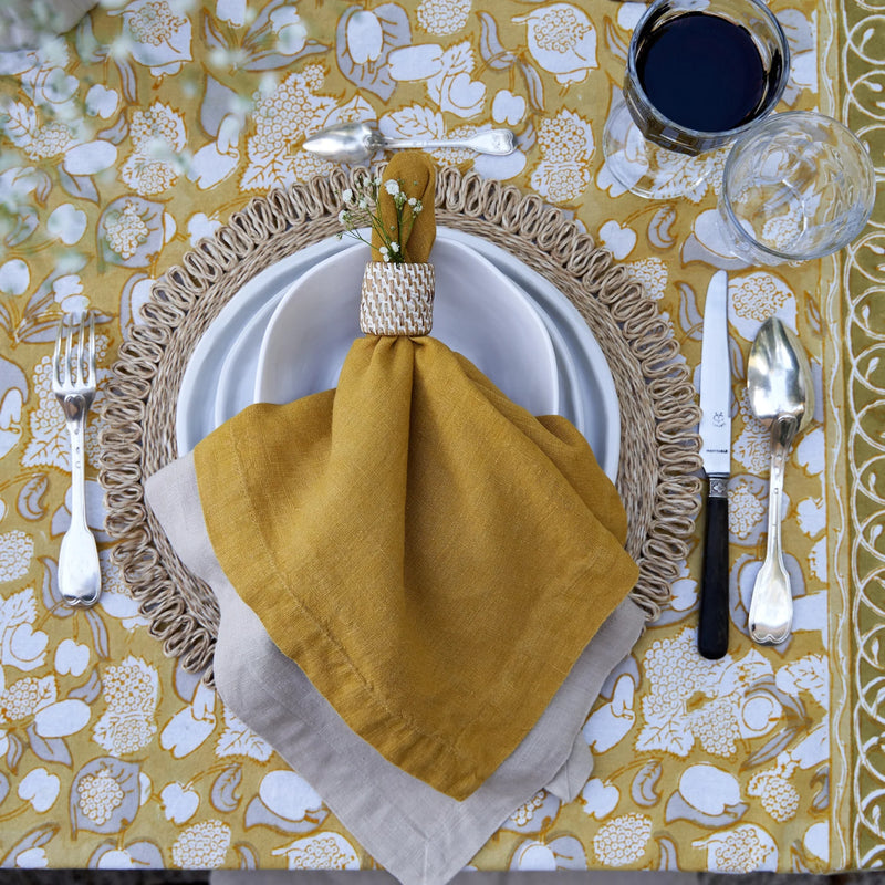 Caravan Home | 21 x 21 Dijon Everyday Napkins Set of 4, displayed on a table with a napkin and glasses, showcasing their oversized, hand-dyed elegance.
