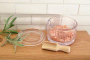 Earth & Nest Salt Pot + Scoop set, featuring a glass container with pink salt and a wooden spoon, designed to enhance your kitchen's elegance and functionality.
