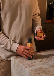 Person holding Holcomb Studio Stone Pepper Mill, highlighting its ergonomic wooden design, part of Athens Cooks' curated kitchen tool collection.