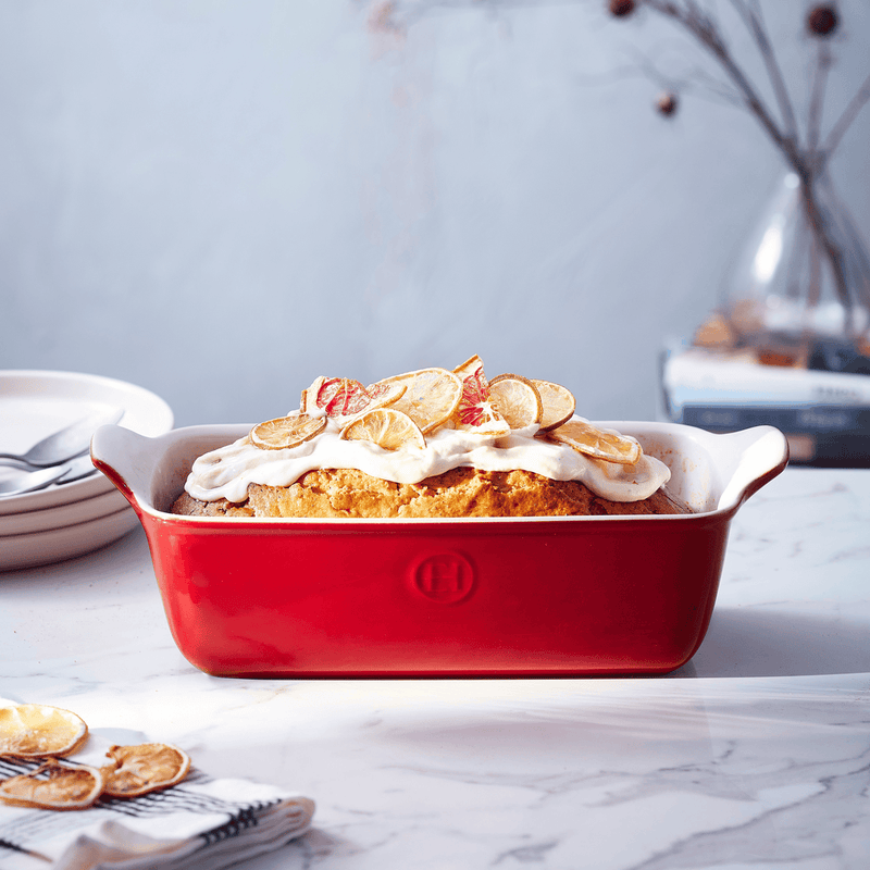 Emile Henry | Modern Classics Loaf Pan, Rouge, 9 x 5, showcasing a frosted citrus loaf with lemon garnish, highlighting the pan's elegant transition from oven to table.