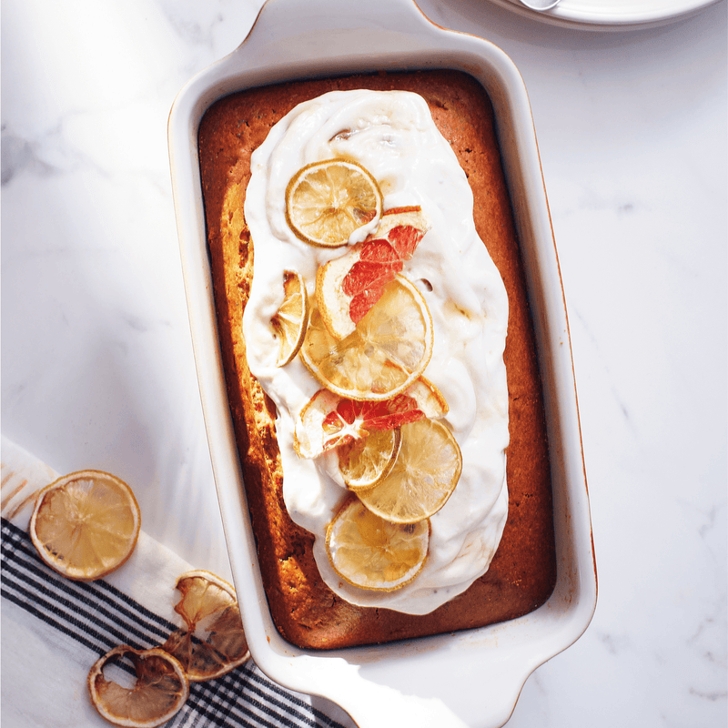 Emile Henry | Modern Classics Loaf Pan, Rouge, 9 x 5 with citrus-topped frosted loaf cake, showcasing even baking and elegant presentation on a marble surface.