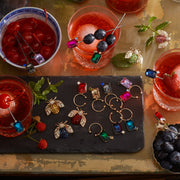 Joanna Buchanan Party Set features elegant cocktail picks and wine charms, displayed with drinks and fruit, perfect for enhancing any celebration.