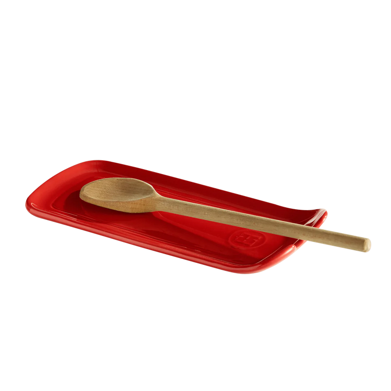Emile Henry | Burgundy Spoon Rest on a red tray, featuring a wooden spoon, designed to keep kitchen surfaces clean and organized while cooking.