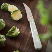 Opinel | Essential Small Kitchen Knife Sets, Primo, featuring a serrated paring knife on a wooden board with Brussels sprouts, ideal for versatile kitchen tasks.