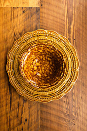 Provvista Designs | Basket Jubilee Cereal Bowl in Honey Tortoise, featuring a scalloped rim and braided border plate, on a wooden table.