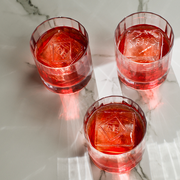 Richard Brendon | Double Old Fashioned Tumbler - Fluted, showcasing a group of elegant, weighty glasses with red liquid and ice, ideal for cocktails.