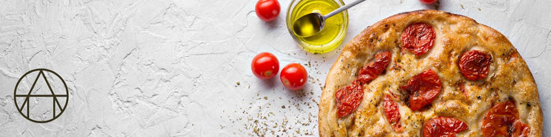 The Perfect Focaccia topped with fresh tomatoes, presented on a table, showcasing its artisanal quality from Athens Cooks.