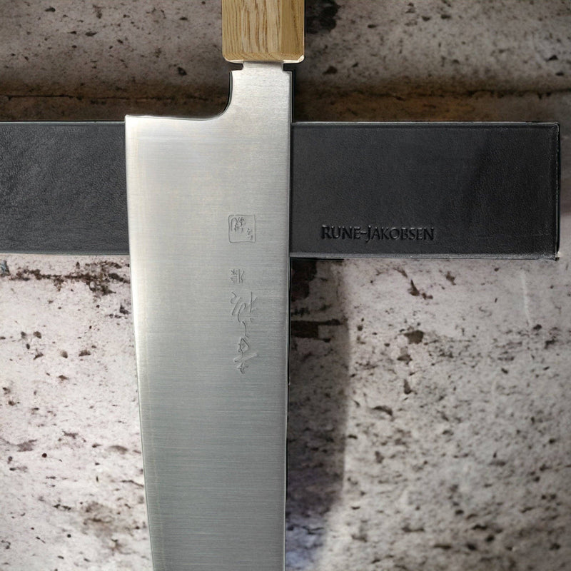 Rune-Jakobsen Design 'Leather protected' knife magnet features a wooden oak rail with a luxurious leather front, designed to securely hold kitchen knives.