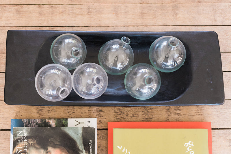 Etú HOME | Clear Sphere Bud Vase displayed on a black tray, showcasing its artisanal design, perfect for single-stem flowers or greenery.