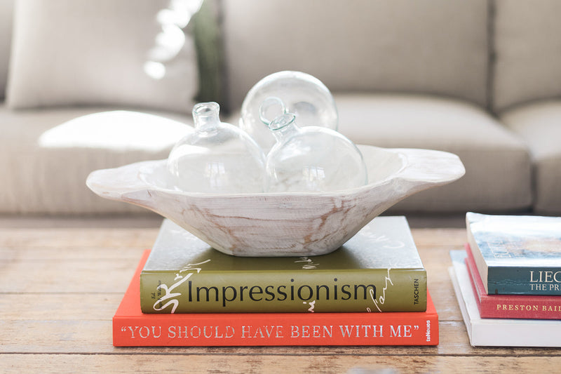Etú HOME | Clear Sphere Bud Vase elegantly displayed on a stack of books, showcasing its unique design for single-stem greenery or flowers.