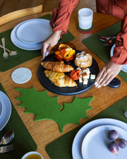Graf Lantz Merino Wool 15 Holly Leaf Trivet in Loden Green placed under a plate of food, showcasing its protective and decorative function in a kitchen setting.
