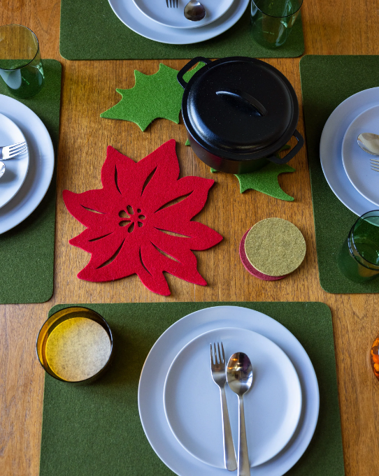 Graf Lantz Merino Wool 15 Holly Leaf Trivet in Loden Green, displayed on a table with plates, utensils, and glasses, enhancing a refined dining setup.