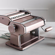 Marcato | Atlas 150 Pasta Maker (Ice) on a table, showcasing its compact design ideal for rolling and cutting fresh homemade pasta.