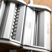 Marcato | Atlas 150 Pasta Maker (Ice) displayed with rollers and adjustable dial for making lasagne, fettuccine, and tagliolini, highlighted for its precision in homemade pasta crafting.