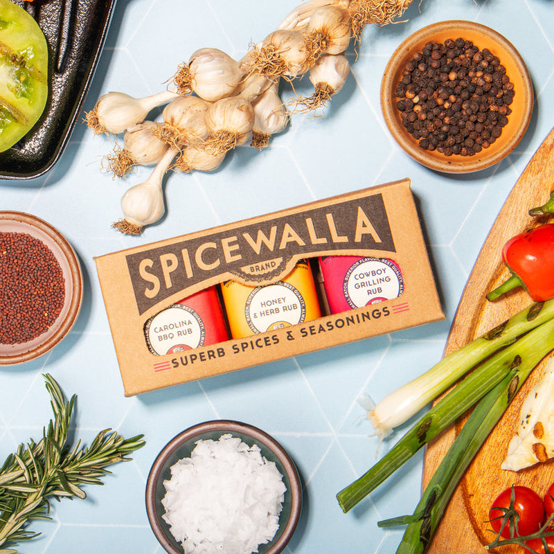 Spicewalla | Grill & Roast Gift Collections, Grill & Roast 3 Pack with rubs, surrounded by fresh ingredients, ideal for enhancing grilled and roasted dishes.