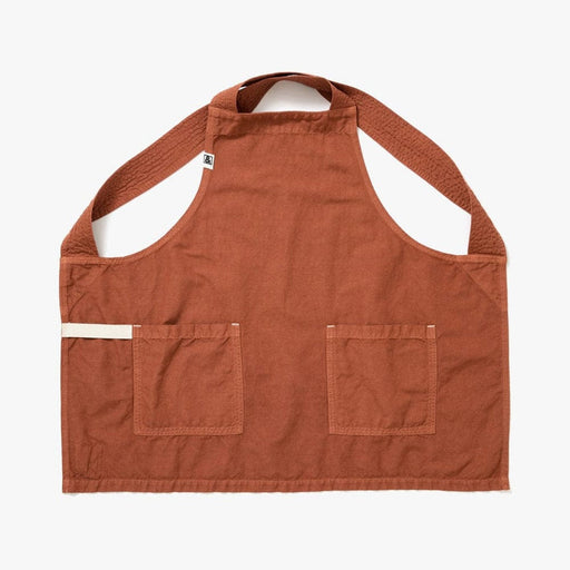 Hedley & Bennett | Harissa - Smock: A rust-orange work apron with neck loop, crossback straps, two front pockets, and a small fabric tab near the left pocket.