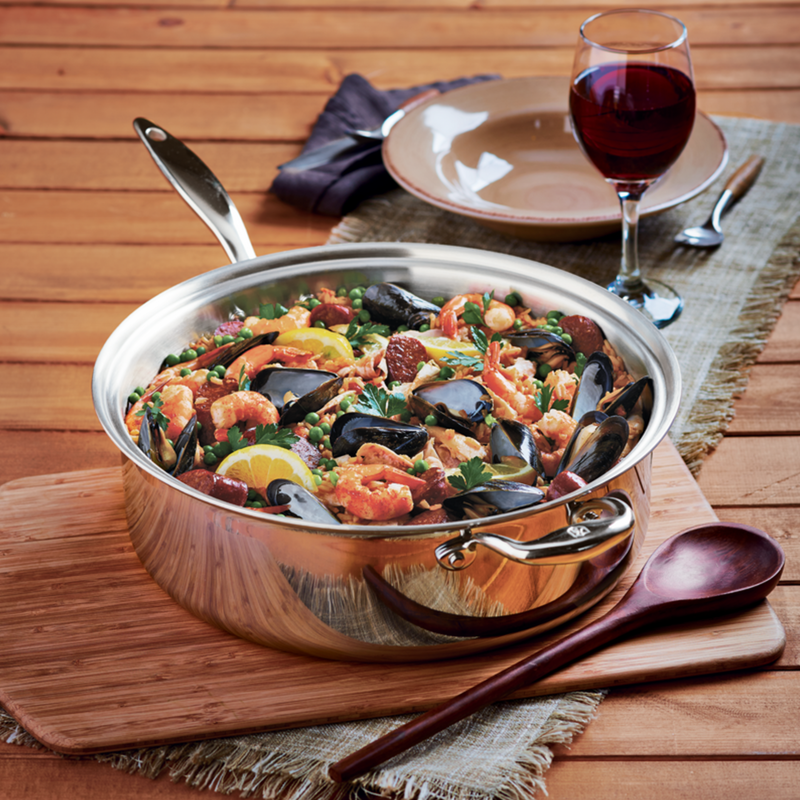 Heritage Steel | Titanium Series 8 Quart Family Sauté with Lid, featuring a pan of seafood beside a glass of wine, highlighting its versatility and craftsmanship.