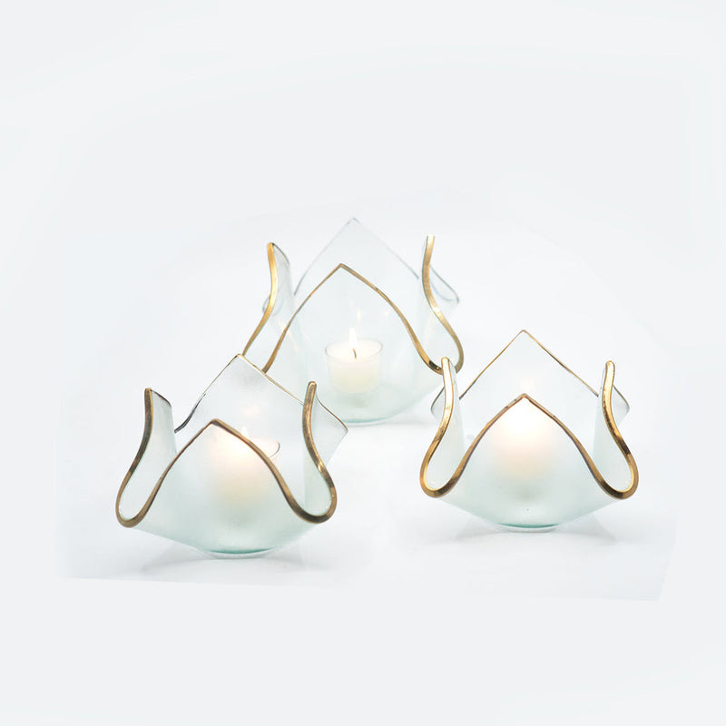 Annie Glass | 4 x 4 x 3 - Single Handkerchief Votive, featuring a frosted, petal-like shape with a gold rim, elegantly holds a lit tea candle.