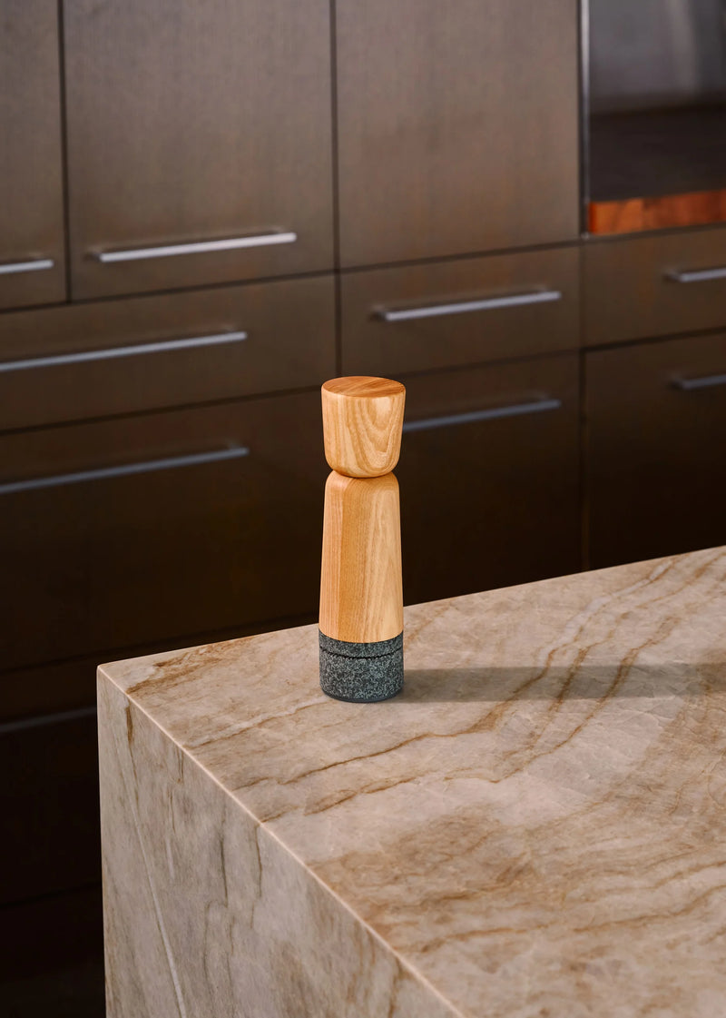 Holcomb Studio Stone Pepper Mill on a countertop, showcasing its sleek wooden design, ideal for enhancing any kitchen tool collection from Athens Cooks.