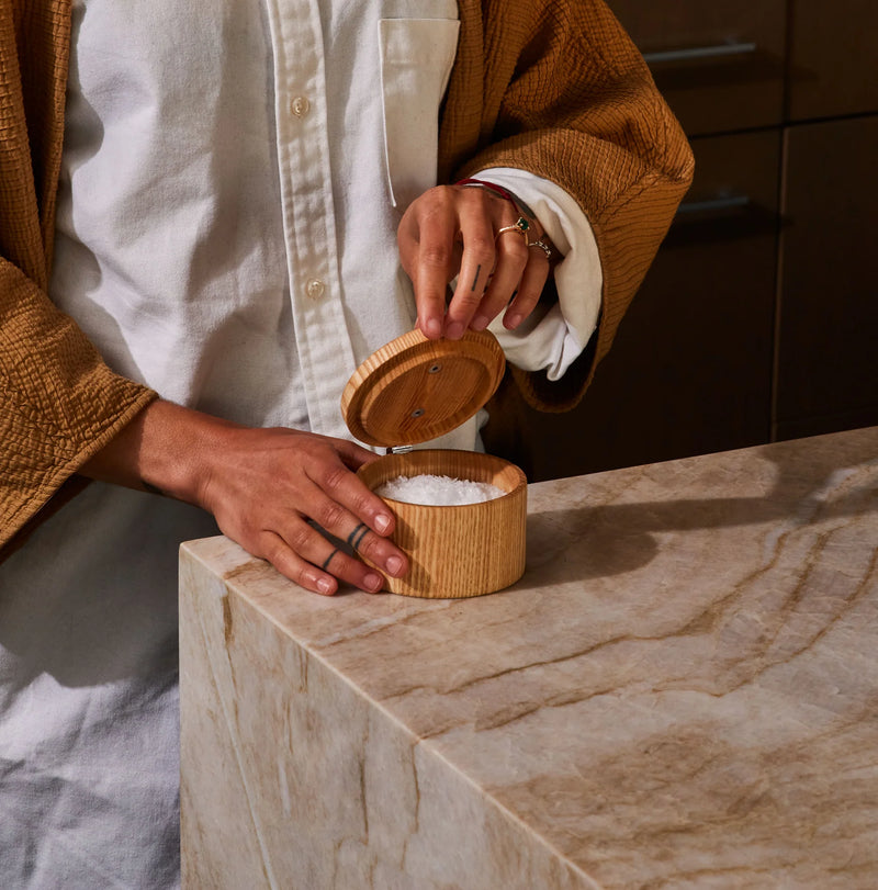 Person holding Holcomb Studio Stash Salt Cellar, a wooden container with an open lid, showcasing salt inside.