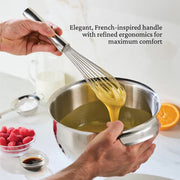 Hestan Stainless Steel French Whisk, 9, held by a person mixing food in a bowl, showcasing its ergonomic design for efficient culinary use.