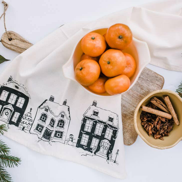 Your Green Kitchen | Holiday Tea Towels - Holiday Houses displayed with bowls of oranges and cinnamon sticks, emphasizing their organic, absorbent cotton material ideal for any kitchen.