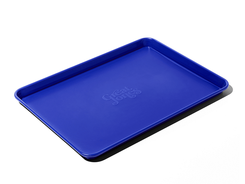 Great Jones | Holy Sheet - Pepper, a blue nonstick ceramic half-sized sheet pan, ideal for effortless baking and serving, showcased against a contrasting background.