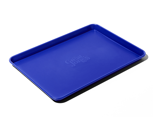Great Jones | Holy Sheet - Pepper, a blue nonstick ceramic half-sized sheet pan, ideal for effortless baking and serving, showcased against a contrasting background.