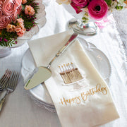 Arte Italica & Crown Linen Designs Hotel Collection Cake Server atop a birthday setting with vintage-style utensils, highlighting handcrafted Italian pewter and stainless steel craftsmanship.