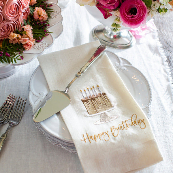 Arte Italica & Crown Linen Designs Hotel Collection Cake Server atop a birthday setting with vintage-style utensils, highlighting handcrafted Italian pewter and stainless steel craftsmanship.