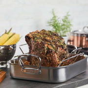 Hestan Provisions Classic Roaster with Rack holding a herb-crusted beef roast, highlighting its 16.5-inch stainless steel design for versatile cooking.