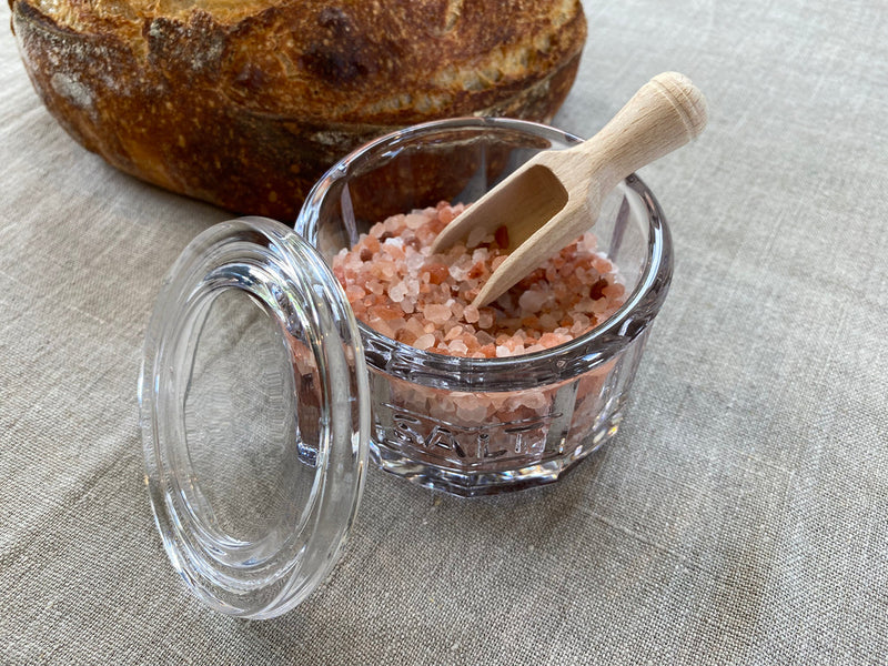 Earth & Nest Salt Pot and Scoop set in glass with wooden spoon, enhancing seasoning presentation in any kitchen setting.