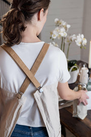 UASHMAMA Apron with Paper Braces - Dark Grey + Platino Brace, held close-up, showcasing its durable design and three front pockets, ideal for kitchen use.