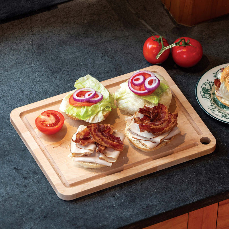 J.K. Adams | Maple Prep Cutting Board with Juice Groove, showcasing open-face sandwiches and tomatoes, ideal for efficient meal prep at Athens Cooks.