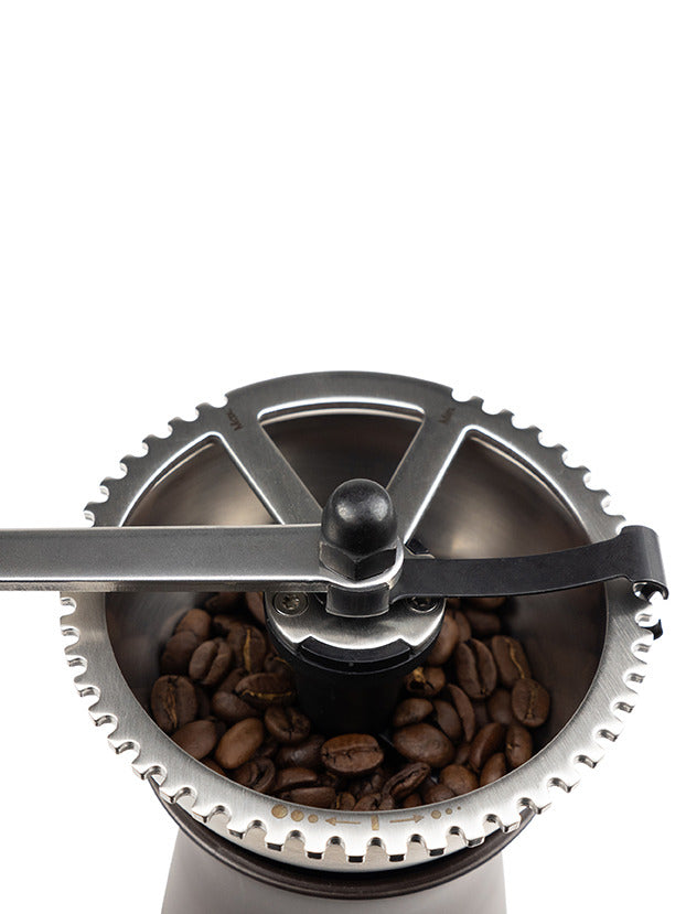 Peugeot | Kronos Coffee Mill, 7.5 inches, featuring a top view of the metal crank handle and adjustment ring, with coffee beans in the hopper ready for grinding.