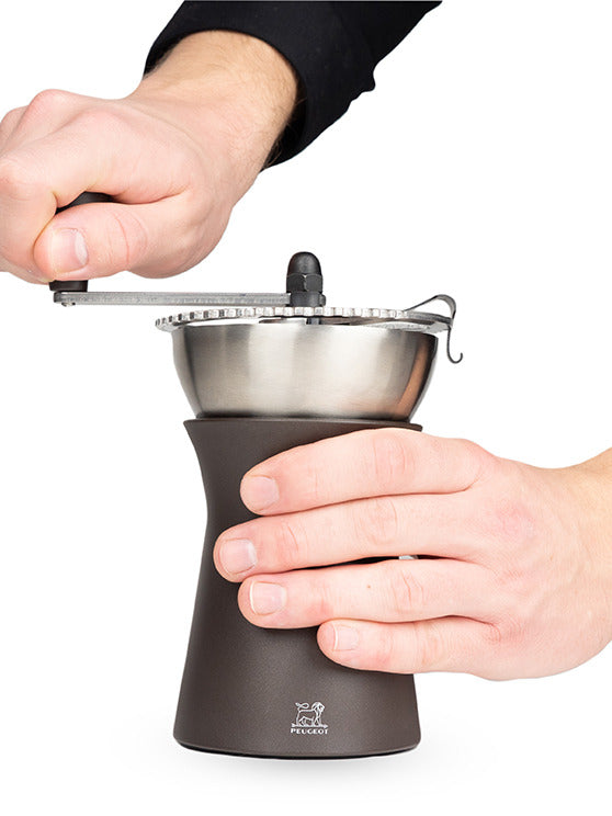 Peugeot | Kronos Coffee Mill, 7.5 inches, shown in use with a hand turning the crank, highlighting its manual burr mechanism for freshly ground coffee.
