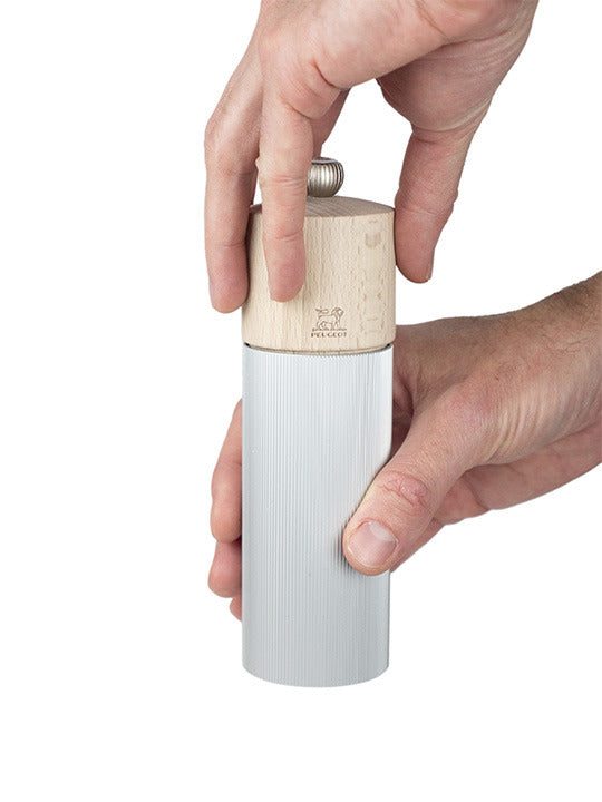 Peugeot | Line Salt Mill Aluminum + Beechwood, 7 inches, with a ribbed aluminum body and wood top, held and twisted in hands, showcasing its Scandinavian-inspired design.