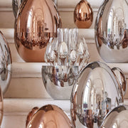 Christofle | MOOD BY CHRISTOFLE 24 Pieces set with polished flatware in a reflective silver egg-shaped case, displayed as an artful kitchen centerpiece.