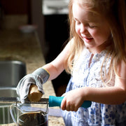Young girl grates ginger using a Microplane while wearing Microplane | Cut Resistant Kitchen Safety Gloves for Adults and Kids, Kids Gloves, ensuring safe culinary exploration.